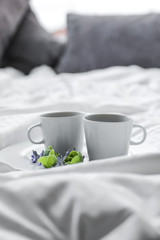 Two white cups of coffee on a white background on a bed in the morning, copy space.