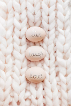 Easter eggs with wishes live, laugh, love for Easter on a knitted blanket