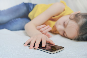 Girl sleeping on a sofa holding an iPhone in her hands