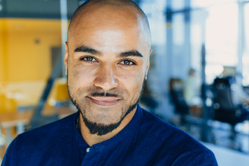 Fototapeta premium Handsome cheerful african american executive business man in office workspace. Concept of young people work in free schedule