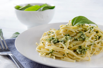 plate of pasta, spaghetti with spinach, fork on a white background close-up