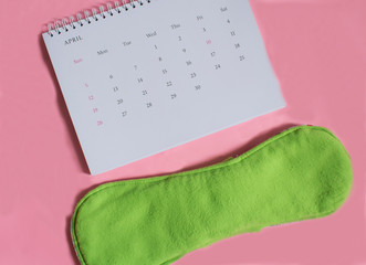 Calendar and disposable menstrual pad. Menstruation or periods concept. Getting pregnant. Time to conceive.