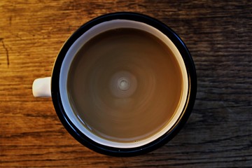 stir latte in a black and white cup in a wooden background
