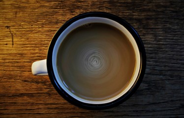 stir latte in a black and white cup in a wooden background