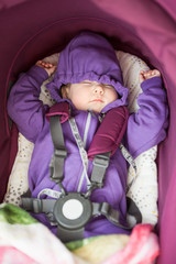 Sleeping baby portrait, lying inside of stroll fastened with safety belt, hands up