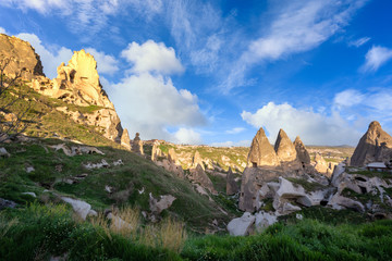 Fototapeta premium Uchisar Castle and the town are sandstone mountains filled with tunnels and windows. In the morning, the sun hits the golden peaks and blue skies of Cappadocia, Turkey.