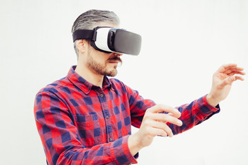 Concentrated man in VR headset touching air. Handsome focused bearded men checkered shirt using virtual headset and moving hands on grey background. Technology concept