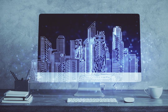 Desktop computer background in office and big town buildings hologram drawing. Double exposure. Smart city concept.