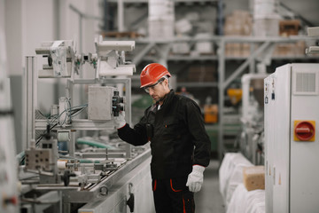 Portrait of worker in factory. Young handsome man working in factory. 