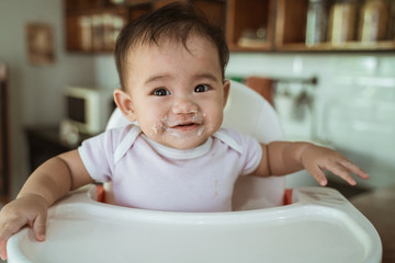 happy asian baby feeding time sitting on highchair
