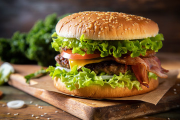 Hamburger with bacon on a wooden board