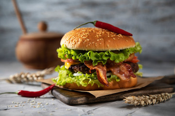 
Hamburger with bacon and chili peppers on a light wooden table
