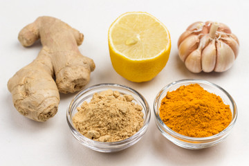 Ginger root, dry ginger and turmeric powder, garlic and lemon on white background.