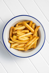 French fries in bowl on white table.