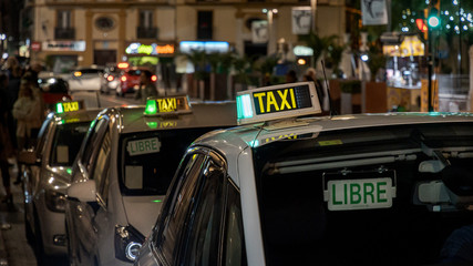 Spanish Taxi signs on the roofs of taxi at night.