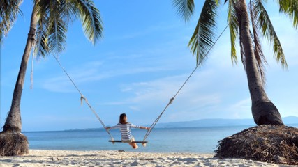 Woman  on swing at tropical island summer time on the sea coast