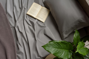 Bed linen in gray, silk fabric texture, bedclothes, the book lies on the bed