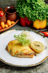 Restaurant dish with vegetable decor on a wooden background. Sea fish fried on a plate with sauce.