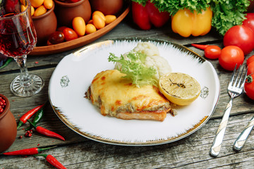 Restaurant dish with vegetable decor on a wooden background. Sea fish fried on a plate with sauce.