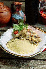 Restaurant dish with vegetable decor on a wooden background. Mashed potatoes with chicken and mushrooms.