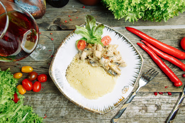 Restaurant dish with vegetable decor on a wooden background. Mashed potatoes with chicken and mushrooms.