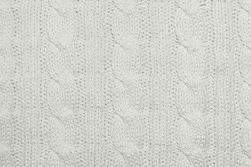 Knitted fabric texture. Machine knitted pigtails on white material. Woolen knitted blanket...