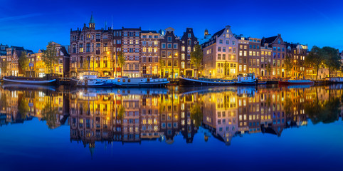 Fototapeta na wymiar Cityscape of Amsterdam at night with reflection of buildings on water