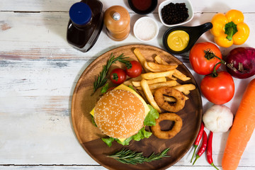 Homemade fresh tasty hamburger side dish with tomato, french fries, ketchub, mastard, salt and pepper on wood plate with white wooden plank background