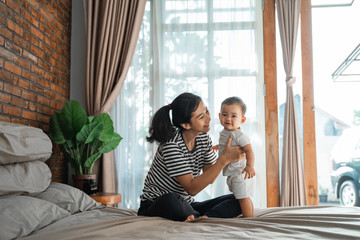 beautiful happy mother playing with her baby on the bed