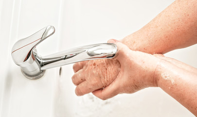 Senior elderly woman wash hands under tap water faucet. Can be used as hygiene illustration concept during coronavirus / covid-19 outbreak prevention