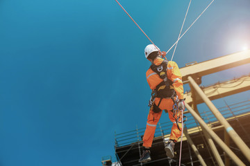 Rope access Safety sprinkling worker on high with scaffolding wearing dresses and safety man with full harness safety concept in site construction building on tower crane background.