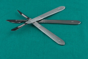 Basic surgical instrument, scalpel with sharp blade on surgical green drape fabric in operation room