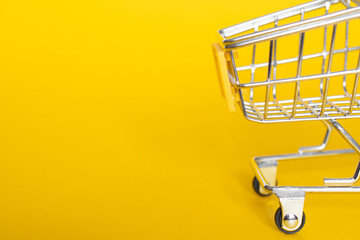 Empty grocery cart on a yellow background: space for text, banner, delivery of necessary products...