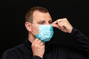 a man puts on a medical mask on his face, instructions on how to wear a mask