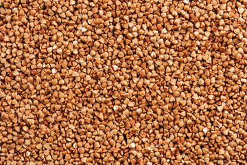 Buckwheat porridge raw evenly scattered on the surface of the texture or background.