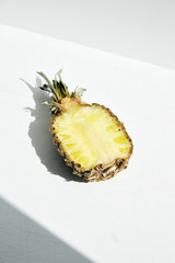 
Half ripe pineapple on a white surface with shadow geometry.