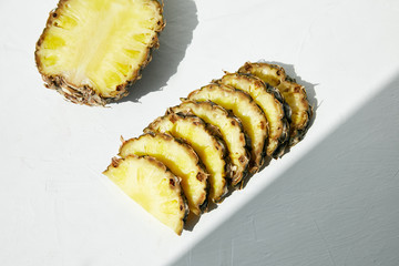 
Sliced ​​ripe pineapple and diagonal shadow on a light background.