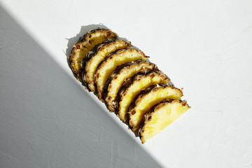 
Slices of juicy ripe pineapple and shadow corner on a white background. Close-up.