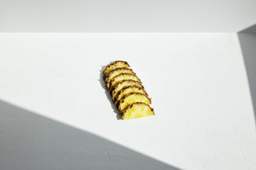
Slices of juicy pineapple with a geometric shadow on white.