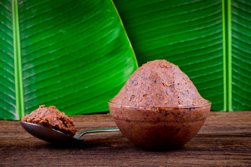 shrimp paste ( kapi ) on brown wood and banana leaf background
