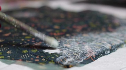 Close up: woman's hand and brush applying glue on material, decoupage
