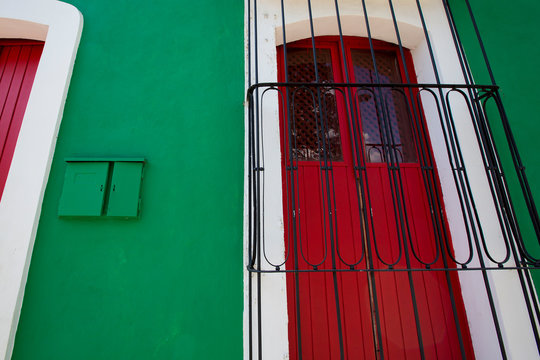 Old colonial architecture in Ciudad Bolivar with green wall and red wooden windows.