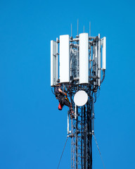 Technician worker climbing on a telephone radio network mast installing new antenna
