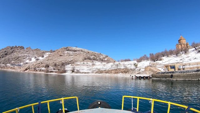 Akdamar island, Van, Turkey - February 2020: Boat traveling towards Akdamar island and surp church Akdamar church. It is an important religious place for the Armenian people
