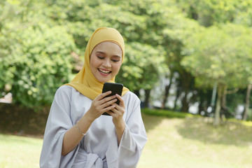 Cheerful Muslim girl using smartphone