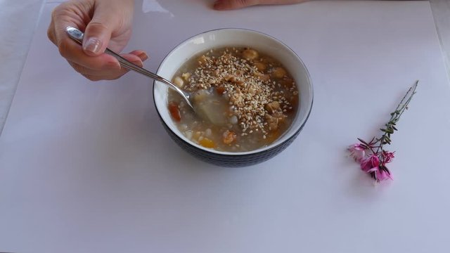 Woman eating Ashure aka Turkish Noah's Pudding with spoon.