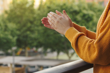 Stock photo of a hands of a young woman clapping from the balcony to support the medical team