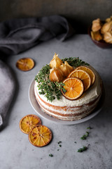 Delicious birthday orange cake decorated with orange slices, physalis and fresh thyme
