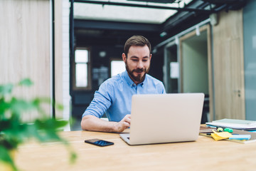 Brown haired man interested in using laptop in office