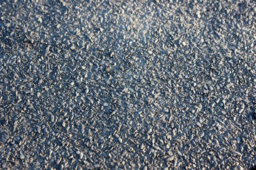 Gray stone cover in large pan. Asphalt with small stones. Black-gray background in the sun. Monochrome texture of small stones for your design. 